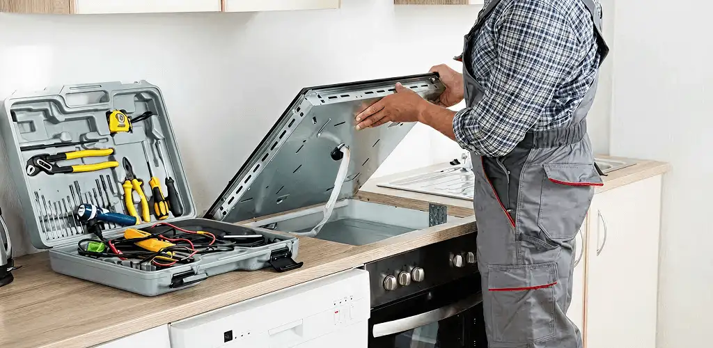 Handyman repairing a cooktop and checking wiring connections in Ann Arbor, MI