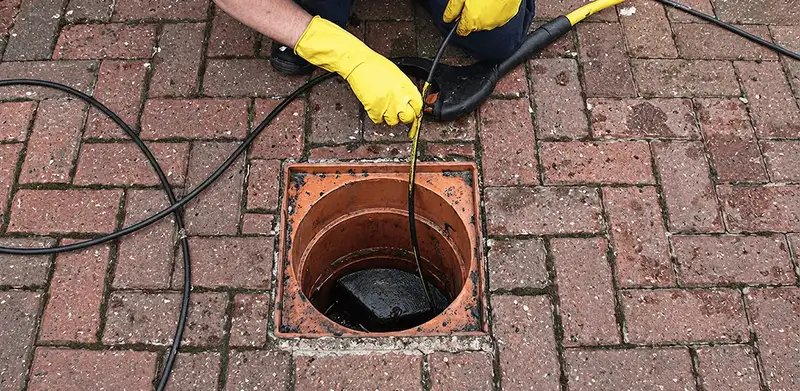 Drain cleaning technician using a drain snake to clear a clogged drain in Ann Arbor, MI