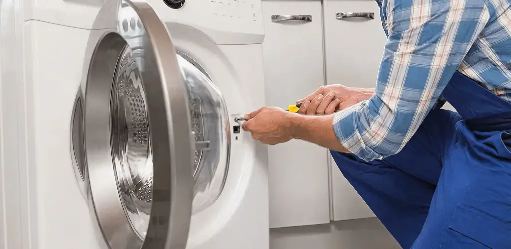 Handyman repairing a clothes dryer and checking electrical connections in Ann Arbor, MI