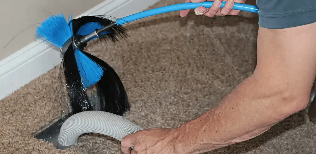 Dryer vent cleaning technician brushing lint from a vent line in Ann Arbor, MI