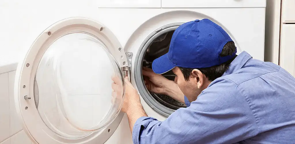 Washing machine repair handyman inspecting a front-load washer drum in Ann Arbor, MI