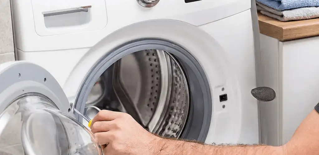 Handyman repairing a front-load washing machine and inspecting the drum in Ann Arbor, MI