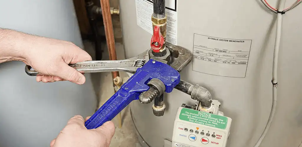 Water heater repair technician tightening the shutoff valve and supply line in Ann Arbor, MI